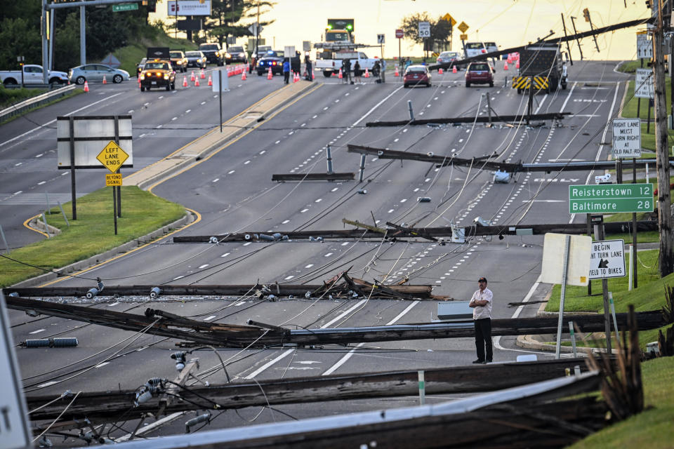 Looking east from Route 97, a man stands in the field of downed power lines and poles on Route 140 in Westminster, Md., Tuesday, Aug. 8, 2023, after powerful storms came through the area Monday evening. (Jerry Jackson/The Baltimore Sun via AP)