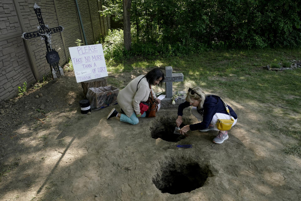 People collect dirt from the gravesite of Sister Wilhelmina Lancaster at the Benedictines of Mary, Queen of Apostles abbey Sunday, May 28, 2023, near Gower, Mo. Hundreds of people visited the small town in Missouri this week to see the nun's body that has barely decomposed since 2019 — some are saying it's a sign of holiness in Catholicism, while others are saying the lack of decomposition may not be as rare as people think. (AP Photo/Charlie Riedel)