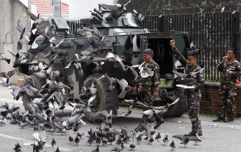 Government soldiers of Task Force Zamboanga feed pigeons with bread crumbs near a military command post during a lull in fighting with Muslim rebels of Moro National Liberation Front (MNLF), in Zamboanga city in southern Philippines September 16, 2013. REUTERS/Erik De Castro