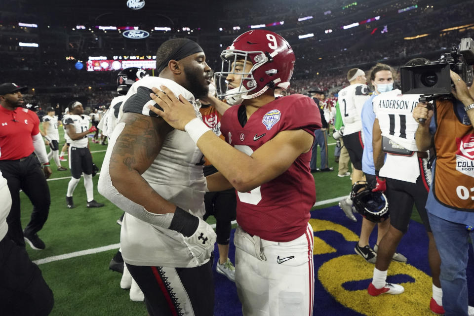 Alabama quarterback Bryce Young (9) hugs Cincinnati defensive lineman Malik Vann (42) after the Cotton Bowl NCAA College Football Playoff semifinal game, Friday, Dec. 31, 2021, in Arlington, Texas. Alabama won 27-6. (AP Photo/Jeffrey McWhorter)