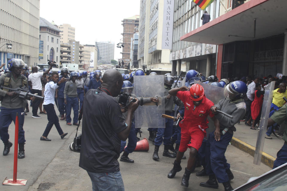 Police surround opposition party supporters who had gathered to hear a speech by the country's top opposition leader in Harare, Wednesday, Nov. 20, 2019. Zimbabwean police with riot gear fired tear gas and struck people who had gathered at the opposition party headquarters to hear a speech by the main opposition leader Nelson Chamisa who still disputes his narrow loss to Zimbabwean President Emmerson Mnangagwa. (AP Photo/Tsvangirayi Mukwazhi)