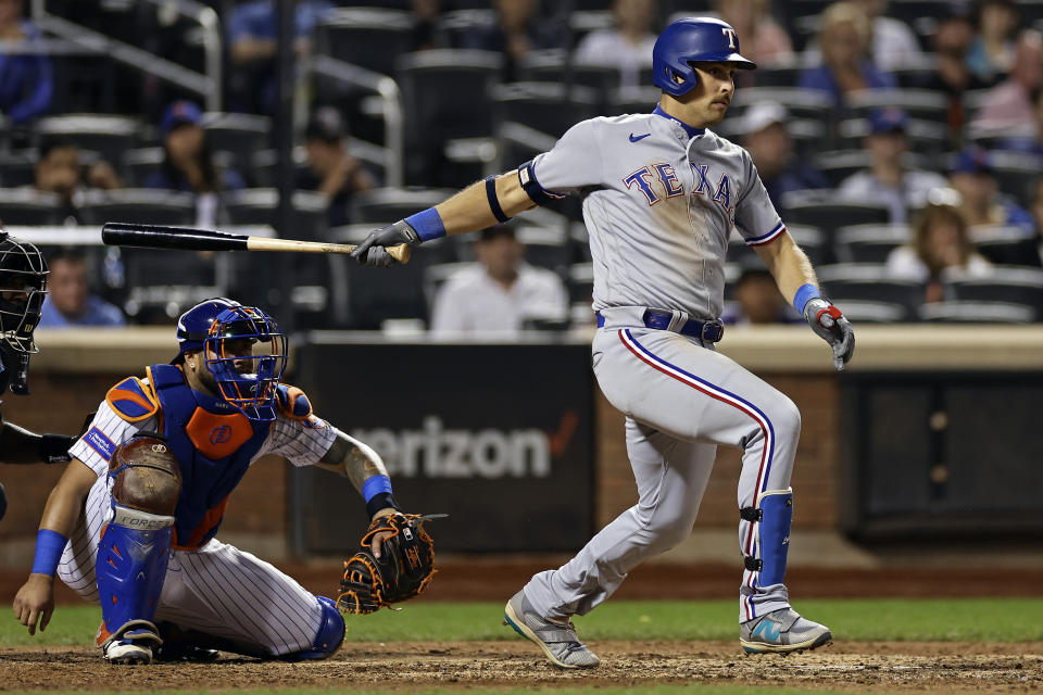 Texas Rangers' Nathaniel Lowe, right, hits a two-RBI single against the New York Mets during the ninth inning of a baseball game on Monday, Aug. 28, 2023, in New York. (AP Photo/Adam Hunger)