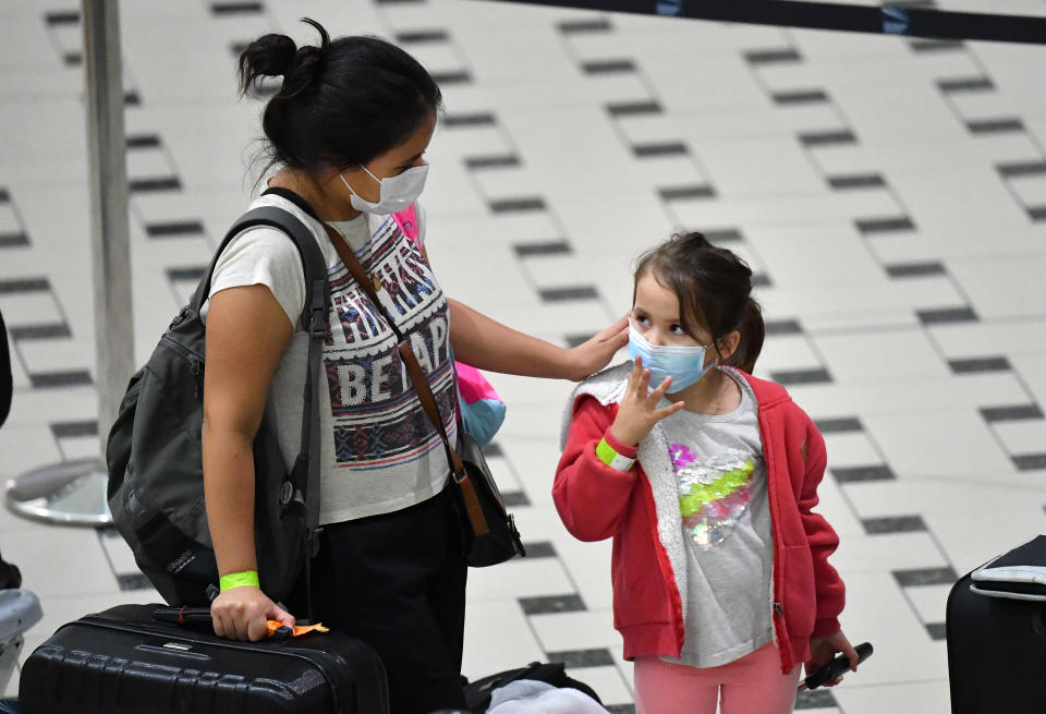 A mother and her daughter who are amongst a group of Australians evacuated from South America due to the COVID-19 pandemic are seen after landing at Brisbane International Airport in Brisbane, Tuesday, April 14, 2020. A Qantas flight from Lima, repatriated 115 passengers back to Australia. AAP Image