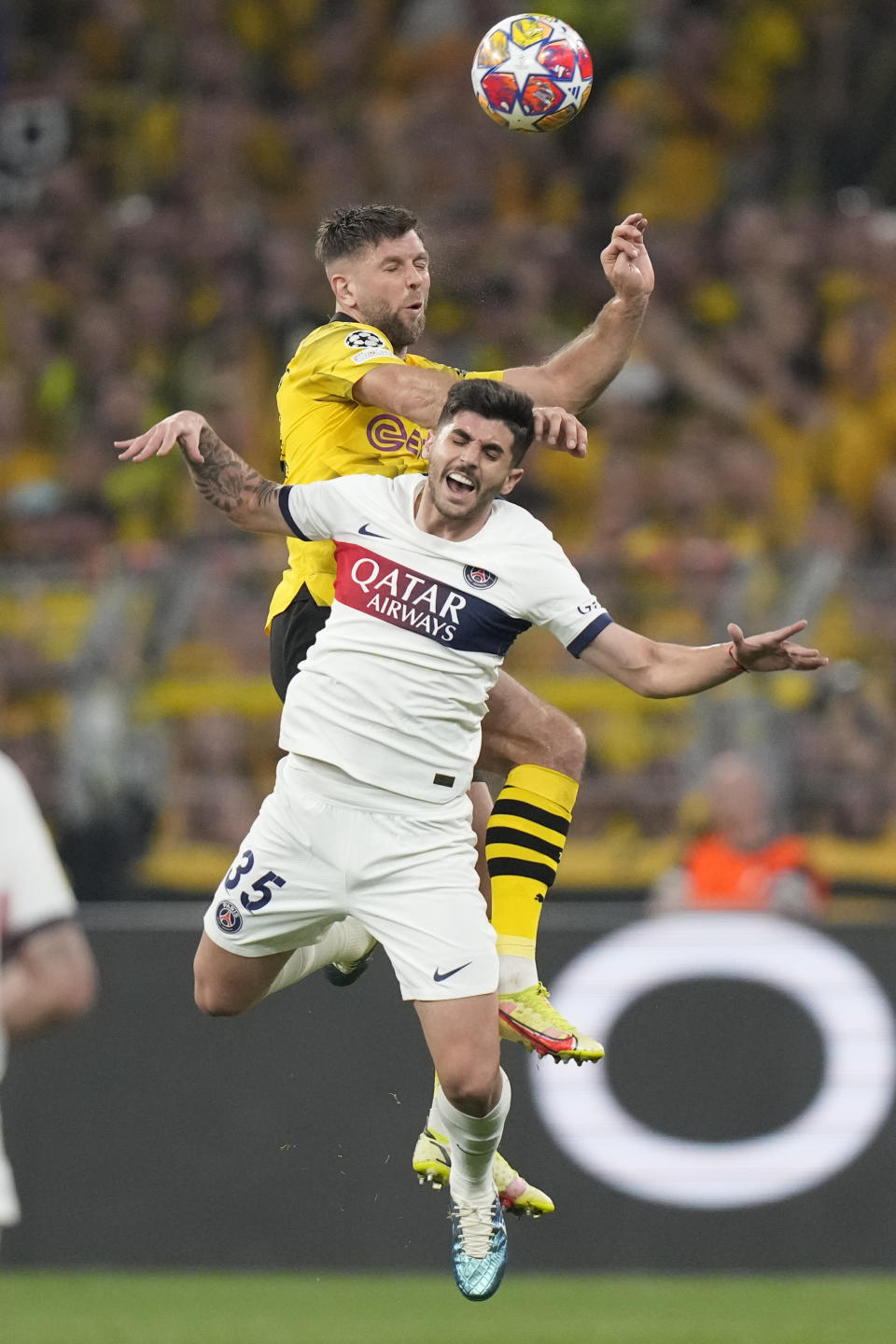 PSG's Lucas Beraldo jumps for a header with Dortmund's Niclas Fuellkrug, rear, during the Champions League semifinal first leg soccer match between Borussia Dortmund and Paris Saint-Germain at the Signal-Iduna Park stadium in Dortmund, Germany, Wednesday, May 1, 2024. (AP Photo/Matthias Schrader)