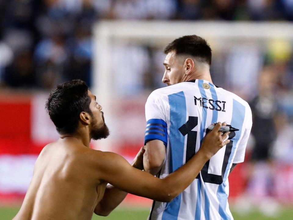 A fan approaches Lionel Messi before asking the Argentina captain to sign his back (AFP via Getty Images)