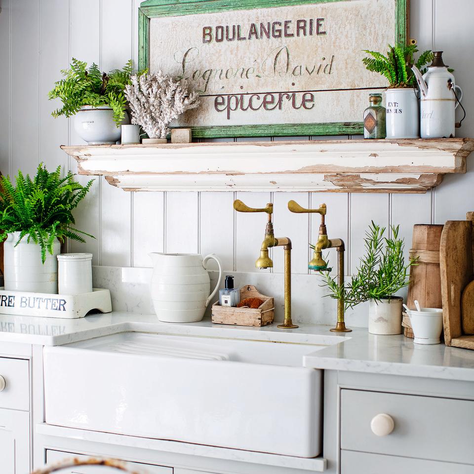 Rustic white kitchen with vintage handles and open shelving.