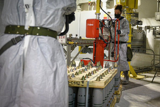 A Pueblo Chemical Agent-Destruction Pilot Plant ordnance technician uses a lift assist to transfer a 105mm projectile onto a conveyor in February 2021.