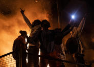 Varias personas celebran haber incendiado una comisaría de policía de Minneapolis este 28 de mayo mientras el edificio arde en llamas tras ellos. (Foto: Stephen Maturen / Getty Images).