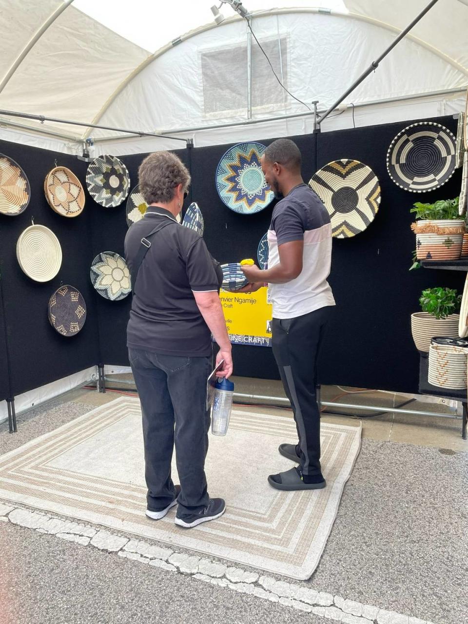 Janvier Ngamije, a fine-craft artist from Lewisville, Texas, discusses a piece of his work with one of the thousands who attended Belleville’s Art on the Square on Saturday, May 20, 2023. The show continues Sunday from 11 a.m. to 5 p.m.