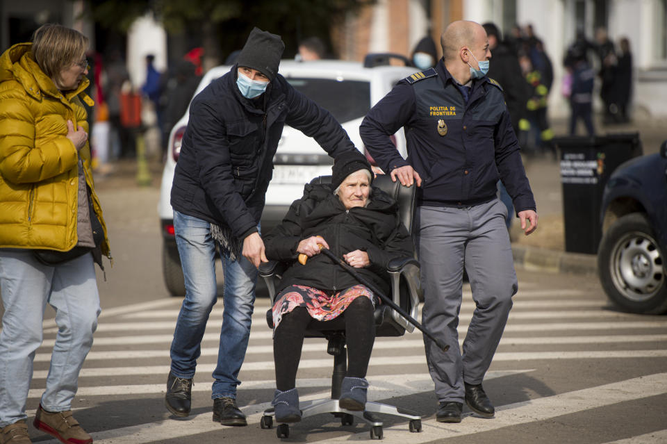 FILE - Border police push an elderly lady in an office chair after fleeing with family the conflict from neighbouring Ukraine, at the Romanian-Ukrainian border, in Siret, Romania, on Feb. 27, 2022. The U.N. refugee agency says more than 4 million refugees have now fled Ukraine following Russia’s invasion, a new milestone in the largest refugee crisis in Europe since World War II. (AP Photo/Alexandru Dobre)