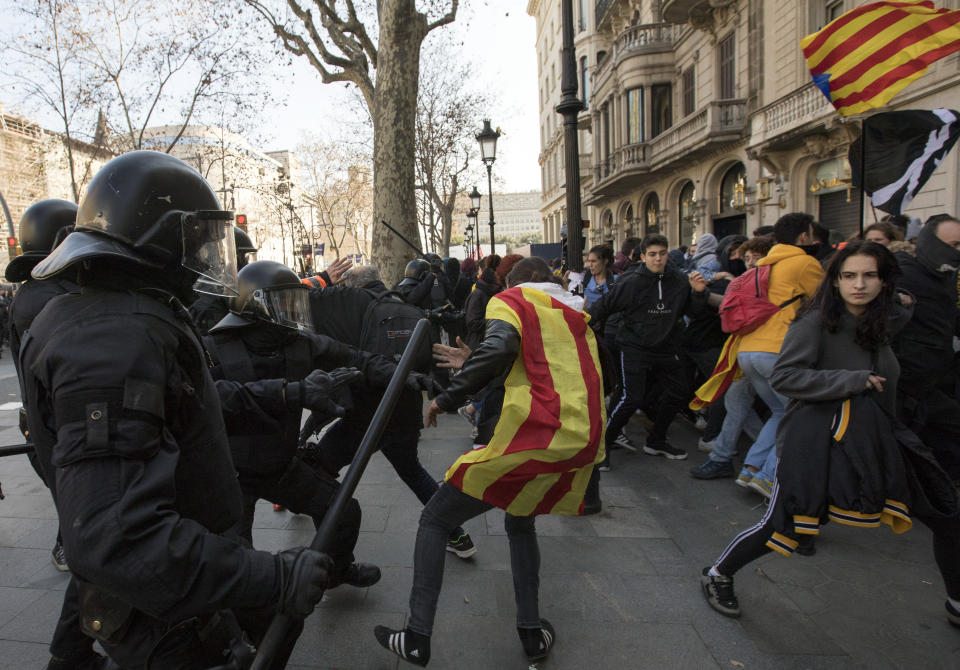 Catalan police officers clash with demonstrators outside a subway after blocking a train rail, during a general strike in Catalonia, Spain, Thursday, Feb. 21, 2019. Protesters backing Catalonia's secession from Spain clashed with police and blocked major roads and train tracks across the northeastern region on Thursday during a strike called to protest the trial of a dozen separatist leaders. (AP Photo/Emilio Morenatti)