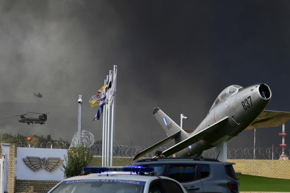 Helicopters operate as smoke rises near an Air Base in Tatoi area, northern Athens, Greece, Tuesday, Aug. 3, 2021. Greece Tuesday grappled with the worst heatwave in decades that strained the national power supply and fueled wildfires near Athens and elsewhere in southern Greece. As the heat wave scorching the eastern Mediterranean intensified, temperatures reached 42 degrees Celsius (107.6 Fahrenheit) in parts of the Greek capital. (AP Photo/Michael Varaklas)