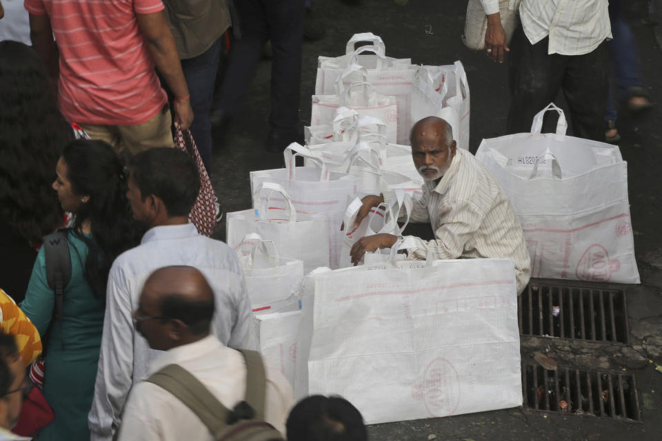 FILE - In this July 5, 2019, file photo, a street vendor wait to sell bags outside a railway station in Mumbai, India. Asian shares advanced Friday, Sept. 20, 2019, and India’s benchmark jumped 5.4% after the government announced plans to cut corporate taxes. (AP Photo/Rafiq Maqbool, File)