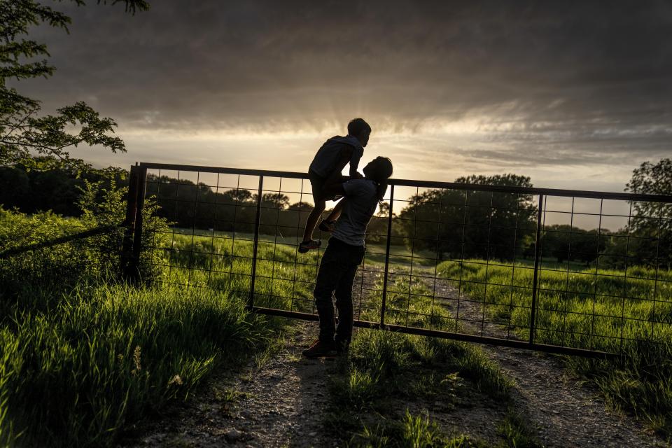 The sun sets as Meredith Ellis looks at cattle with her son, GC, 6, on their ranch in Rosston, Texas, Thursday, April 20, 2023. Ellis has seen how global warming is altering her land. She calls it an "existential crisis," the backdrop to the endless to-do list that comes with regenerative ranching. After a long day, she likes to take a moment to remember why she does it. Standing with her 6-year-old son on a cool evening, they watch over a gate as dozens of cows graze amid the lush grass and a setting sun. "I could stand here all evening," she says. "I just love them." (AP Photo/David Goldman)