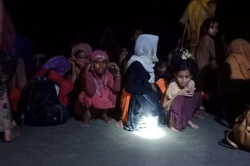 Rohingya refugees who were rescued by Bangladesh Coast Guard, sit on the shore in Teknaf