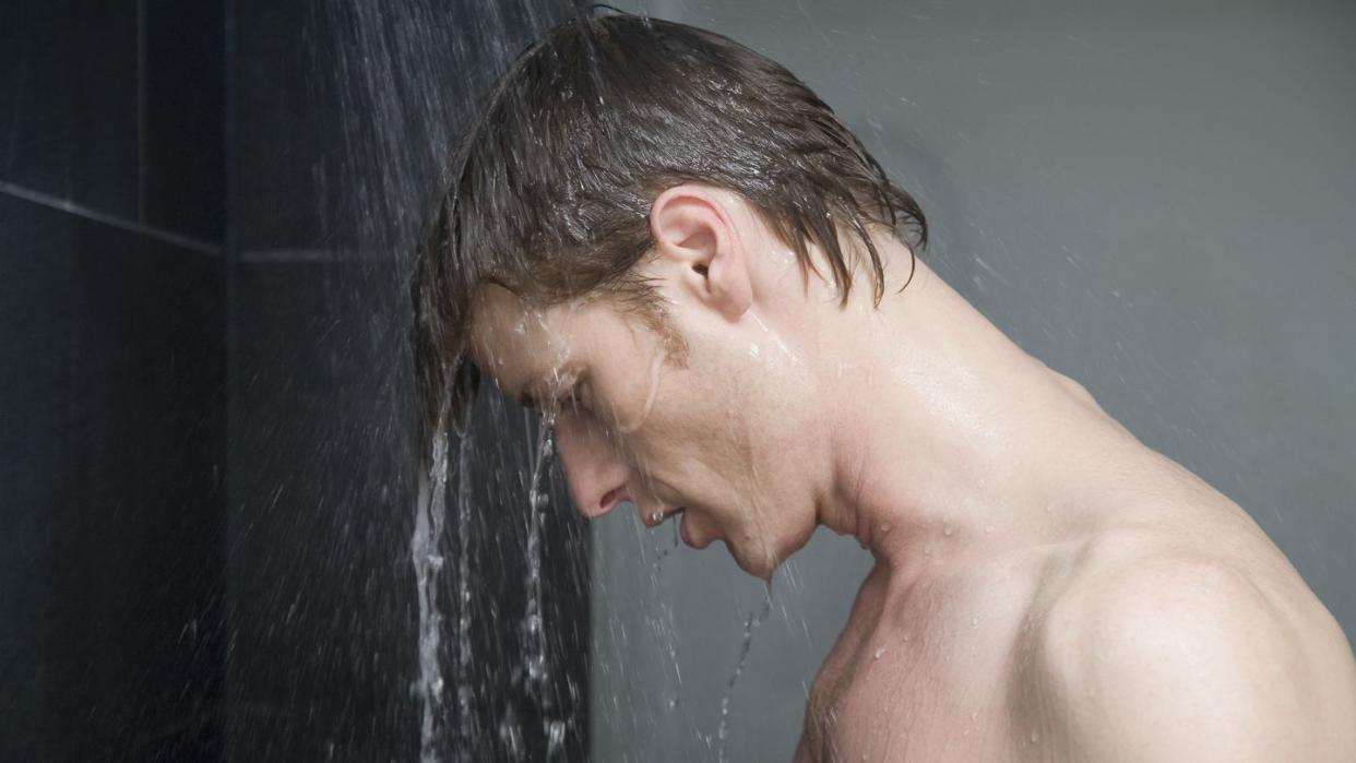 man standing in shower and looking down