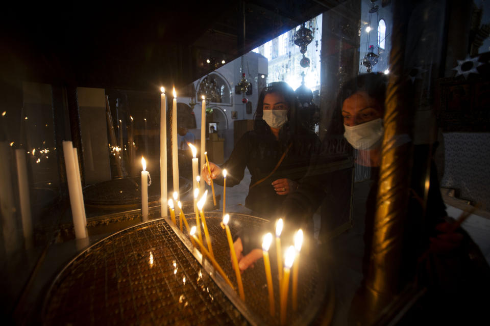 Christian worshiper light candles in the Church of the Nativity, traditionally believed to be the birthplace of Jesus Christ, in the West Bank city of Bethlehem, Monday, Nov. 23, 2020. Normally packed with tourists from around the world at this time of year, Bethlehem resembles a ghost town – with hotels, restaurants and souvenir shops shuttered by the pandemic. (AP Photo/Majdi Mohammed)