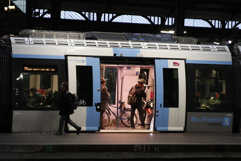 Commuters walk to get on a train at the Gare Saint Lazare station in Paris, France, Monday, Dec. 16, 2019. French transport strikes against a planned overhaul of the pension system entered their twelfth day Monday as French president Emmanuel Macron's government remains determined to push ahead with its plans. (AP Photo/Francois Mori)