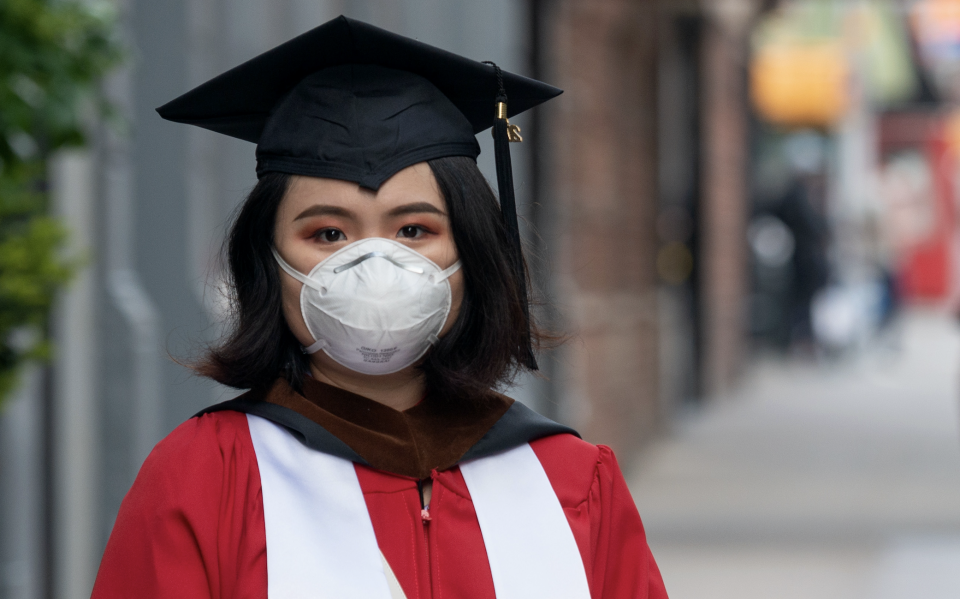 A student wearing a mask, gloves, graduation cap, and gown poses amid the coronavirus pandemic on May 14, 2020 in New York City. (Photo: Alexi Rosenfeld/Getty Images) 