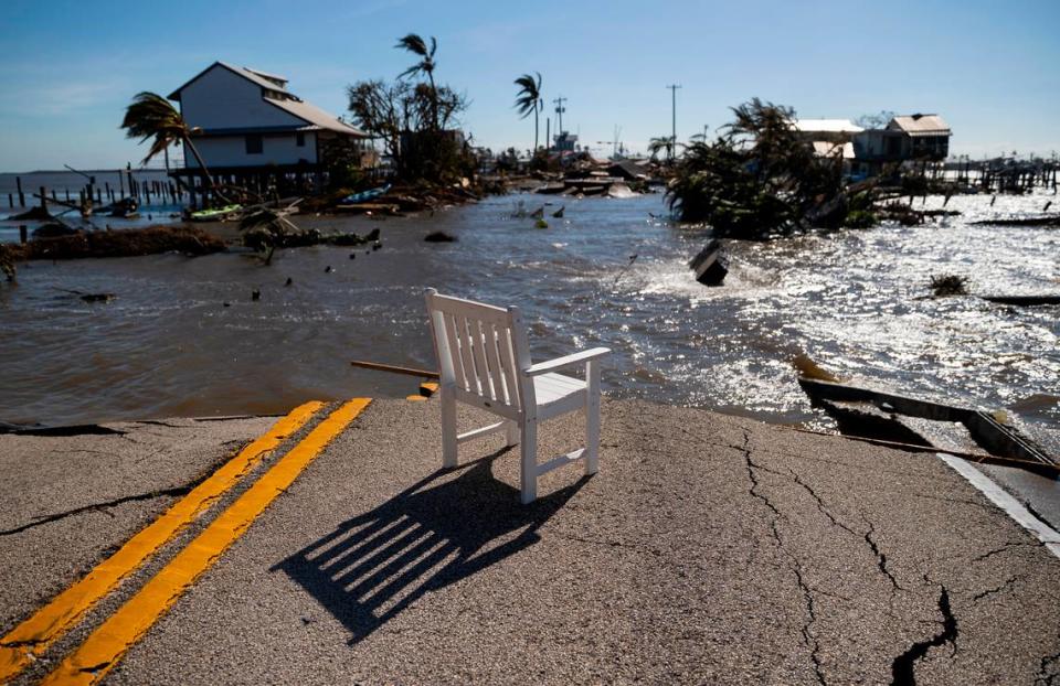 Gulf water flows through a broken section of Pine Island Road on Thursday in Matlacha. The white chair came from the surrounding ruins.