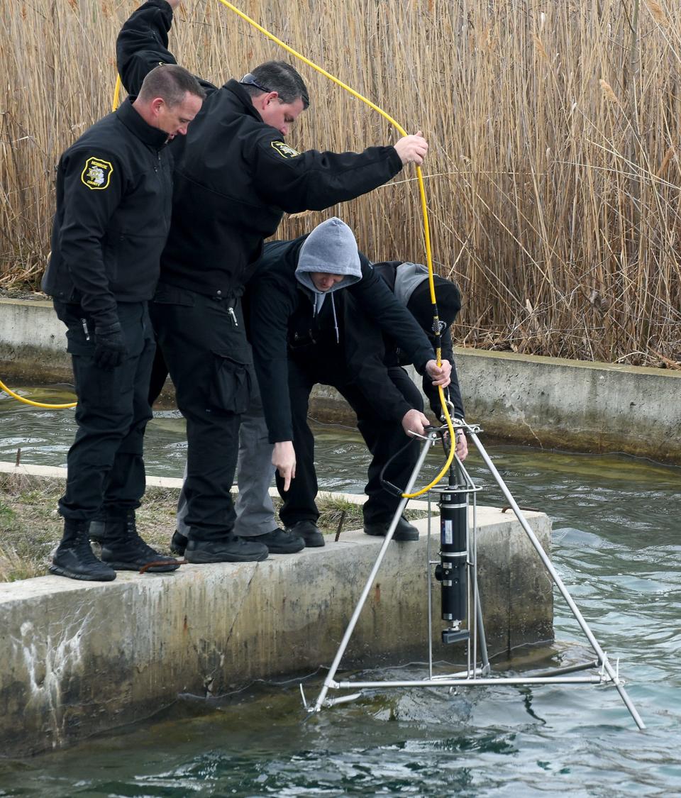 Monroe County Sheriff Dept. Lt. Brian Francisco, left, Deputy Dave Moore, Deputy Mike Stah and diver Brian Paules of the Monroe County Sheriff Underwater Dive and Rescue Team lower the Kongsberg MS 1000 360-degree sonar machine into Lake Monroe in Monroe Charter Township for the first time.