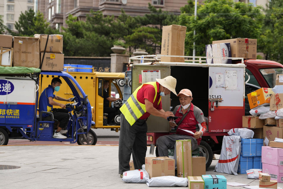 Delivery men sort out their deliveries on the street in Beijing, Monday, Aug. 15, 2022. China’s central bank trimmed a key interest rate Monday to shore up sagging economic growth at a politically sensitive time when President Xi Jinping is believed to be trying to extend his hold on power. (AP Photo/Ng Han Guan)