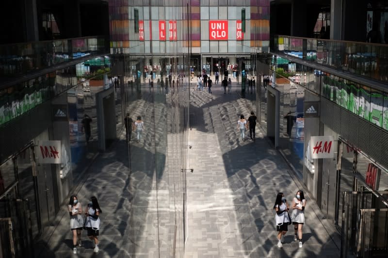 People walk past H&M and the Fast Retailing's Uniqlo stores at a shopping complex in Beijing