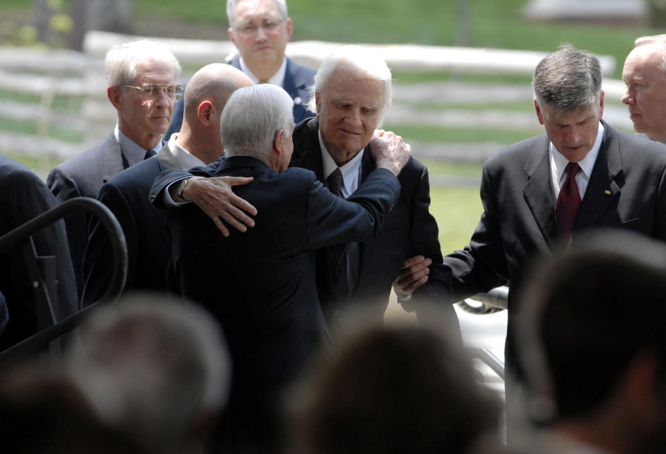 CHARLOTTE, NC - MAY 31:  Evangelist Billy Graham (C) is greeted by former U.S. President Jimmy Carter as he arrives on the stage during the Billy Graham Library Dedication Service on May 31, 2007 in Charlotte, North Carolina. Approximately 1500 guests attended the private dedication ceremony for the library, which chronicles the life and teachings of Evangelist Billy Graham. Former U.S. Presidents Bill Clinton, Jimmy Carter and George H.W. Bush made short speeches during the dedication ceremony. Billy Graham's son, Franklin Graham (R), helps him on stage. (Photo by Davis Turner/Getty Images)