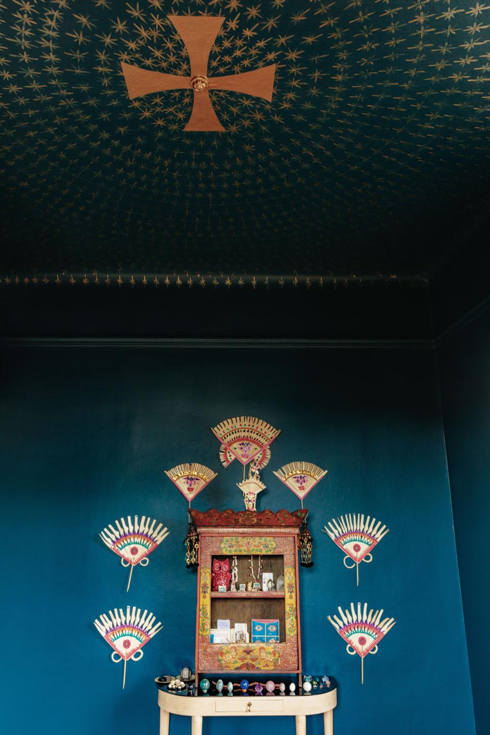 In the meditation room, Balinese palm-frond fans surround an antique Tibetan altar on a vintage Italian console; ceiling painted by artist Jay C. Lohmann.