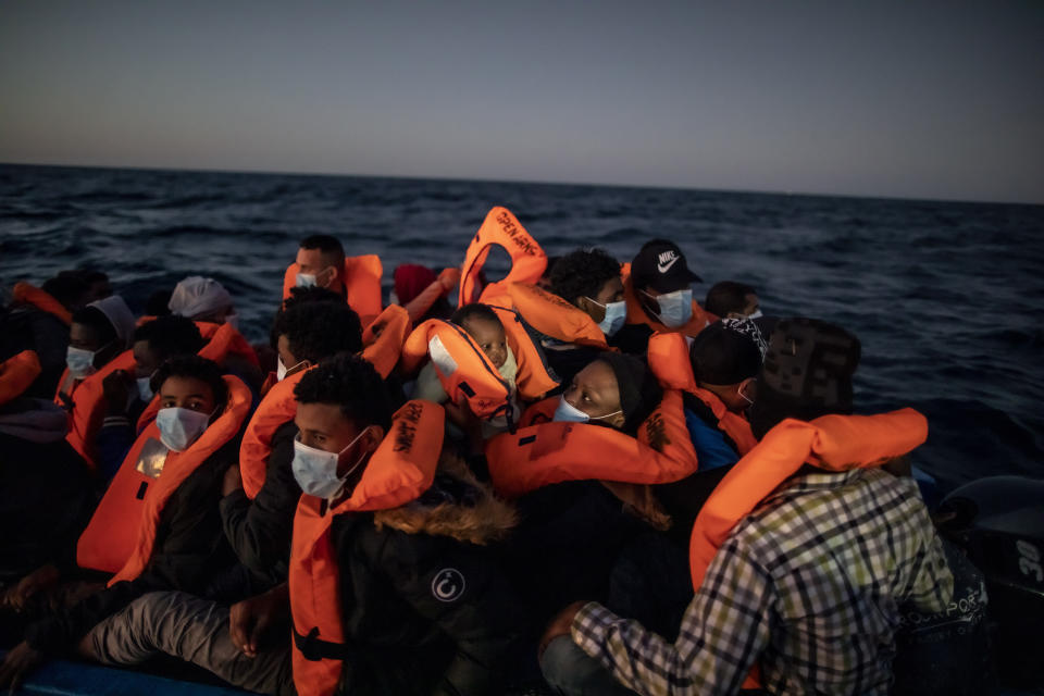 Sandrine, una mujer camerunesa de 33 años, sostiene a su hijo Moise, de tres meses, mientras migrantes y refugiados africanos esperan la ayuda de los rescatistas de la ONG española Open Arms en una atestada balsa neumática en aguas internacionales del Mar Mediterráneo, a 122 millas de la costa de Libia, el 12 de febrero de 2021. En los últimos días, las autoridades libias han impedido ocho intentos de rescate por parte del Open Arms, el barco de la ONG española del mismo nombre, acosando y amenazando a su tripulación. (AP Foto/Bruno Thevenin)