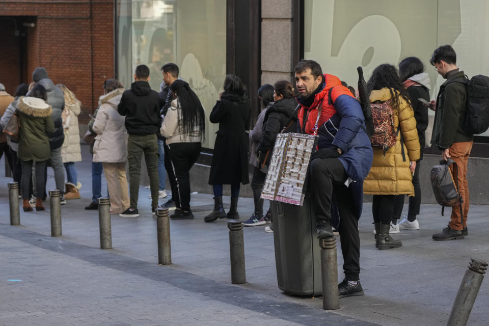 A lottery seller stands by a queue of people waiting to buy tickets from the Dona Manolita lottery shop, in Madrid, Spain, Wednesday, Dec. 20, 2023. The traditional Spanish Christmas lottery draw, known as El Gordo or The Fat One will take place on Dec. 22. (AP Photo/Paul White)