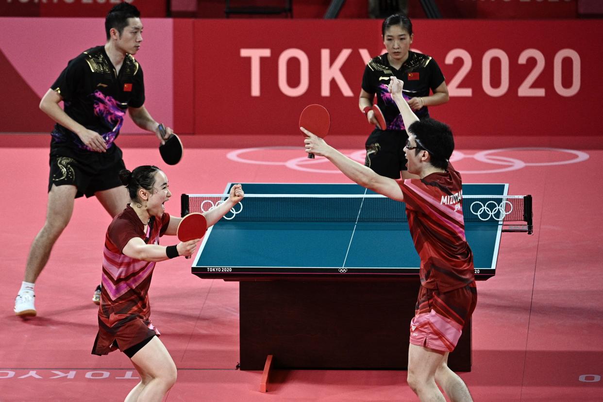 Japan's Jun Mizutani (R) and Mima Ito (2L) celebrate beating China's Xu Xin (L) and Liu Shiwen (TOP R) in their mixed doubles table tennis final match at the Tokyo Metropolitan Gymnasium during the Tokyo 2020 Olympic Games in Tokyo on July 26, 2021. (Photo by Anne-Christine POUJOULAT / AFP) (Photo by ANNE-CHRISTINE POUJOULAT/AFP via Getty Images)