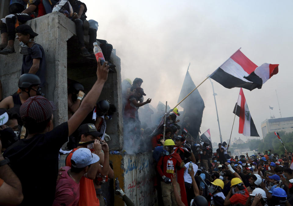 Anti-government protesters control the barriers while Iraqi security forces fire tear gas and close the bridge leading to the Green Zone, during a demonstration in Baghdad, Iraq, Tuesday, Oct. 29, 2019. (AP Photo/Hadi Mizban)