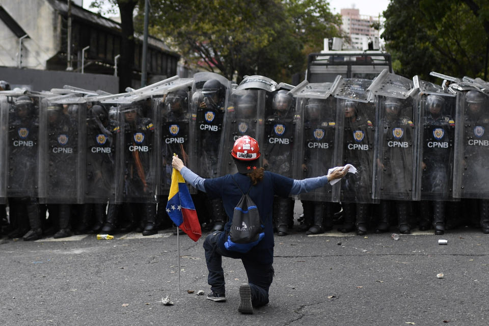 A man kneels in front of police blocking a march called by opposition political leader Juan Guaido in Caracas, Venezuela, Tuesday, March 10, 2020. U.S.-backed Venezuelan political leader Guaido called for the march aimed at retaking the National Assembly legislative building, which opposition lawmakers have been blocked from entering. (AP Photo/Matias Delacroix)