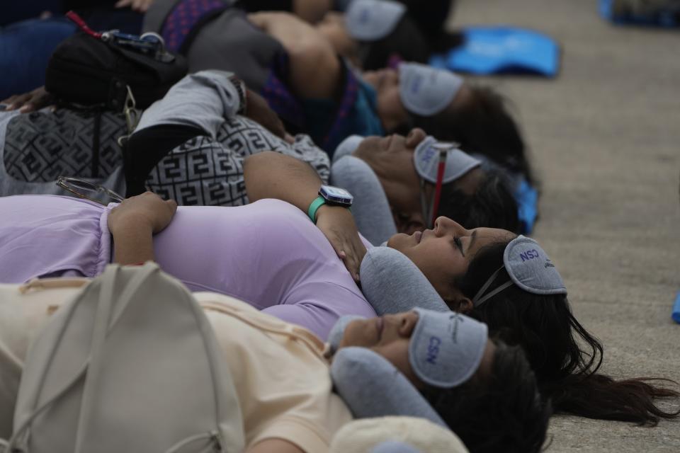 Equipped with mats, sleeping masks and travel pillows, people lie sprawled out at the base of the iconic Monument to the Revolution to take a nap, in Mexico City, Friday, March 15, 2024. Dubbed the “mass siesta,” the event was in commemoration of World Sleep Day. (AP Photo/Fernando Llano)