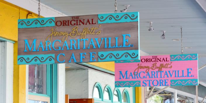 from a ceiling hang two signs with the inscription "The Margaritaville Café of the Original Jimmy Buffet" and "Original Jimmy Buffet's Margaritaville Store"