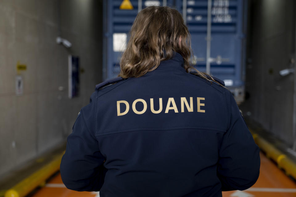 A customs officer, posing for the media, watches as a truck carrying a container enters an X-ray cargo scanning facility at the Maasvlakte container terminal location in the port of Rotterdam, Netherlands, Monday, Jan. 9, 2023. Cocaine is spreading at an alarming rate through Europe, much of it through the world ports of Antwerp and Rotterdam. And a Tuesday, Jan. 10. 2023, announcement of massive seizures may well hide a bigger truth, that South American cartels are throwing ever more cocaine at the European market. (AP Photo/Peter Dejong)