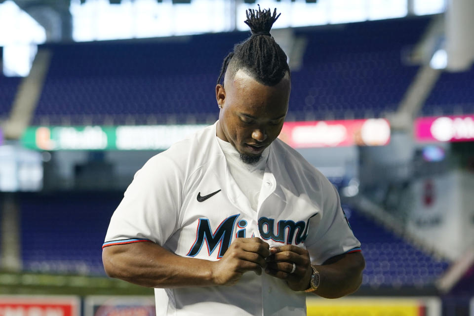 Miami Marlins baseball infielder Jean Segura puts on a Marlins jersey before posing for a photograph, Wednesday, Jan. 11, 2023, in Miami. Segura recently signed a two-year deal with the Marlins. (AP Photo/Lynne Sladky)