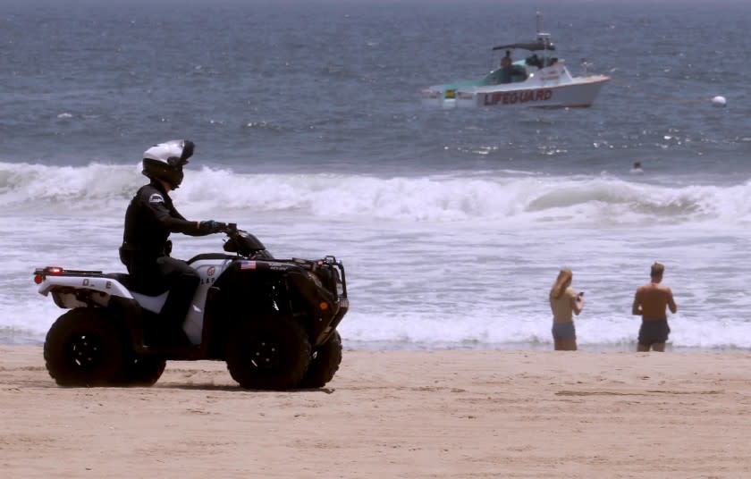 VENICE, CA - JULY 05, 2020 - - A police officer and a lifeguard boat comb the shoreline in Venice Beach on July 5, 2020. Even though the beach was closed this weekend a few still made their way to the shoreline. In what officials have described as an "alarming" increase, hospitalizations of patients with confirmed coronavirus infections in Los Angeles County have jumped 41% in the last three weeks. On Friday, there were 1,947 patients in L.A. County hospitals with confirmed coronavirus infections; seven days earlier, there were 1,717; the week before that, there were 1,426; and the week prior to that, there were 1,383. (Genaro Molina / Los Angeles Times)