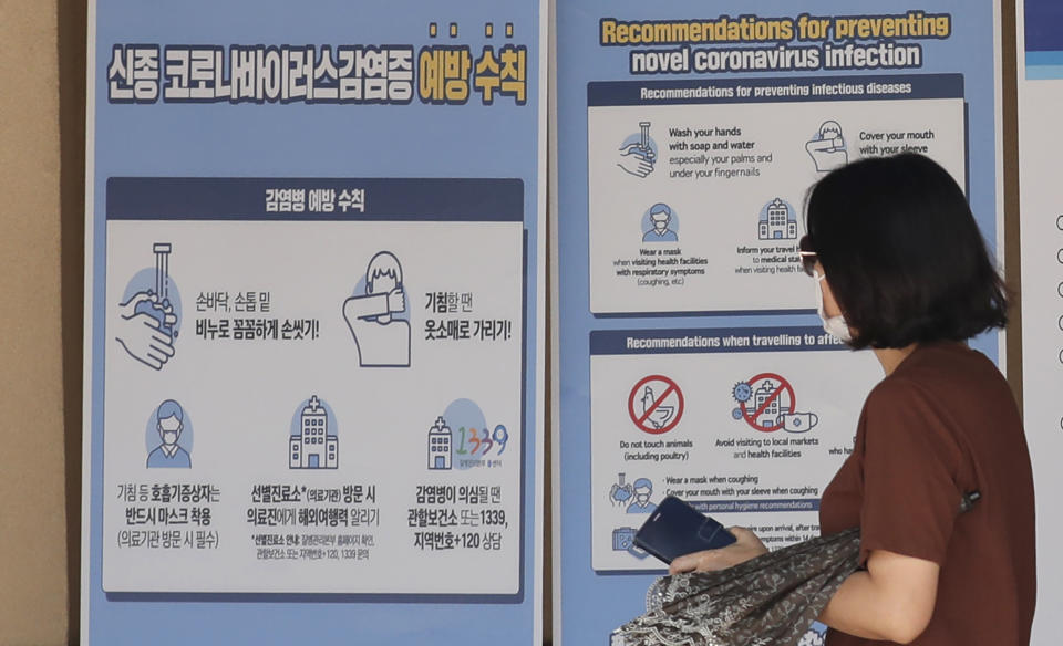 A visitor wearing a face mask walks near a banner showing precautions against the coronavirus at the Gyeongbok Palace, one of South Korea's well-known landmarks, in Seoul, South Korea, Sunday, Aug. 16, 2020. (AP Photo/Lee Jin-man)