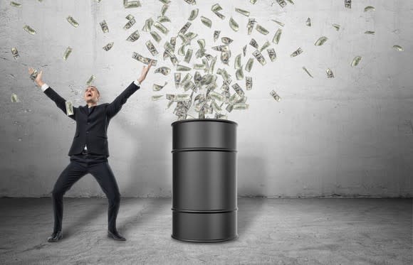 A man in a suit with arms open wide as money shoots out of an oil barrel beside him.