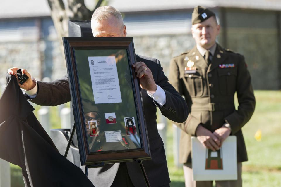 Retired Lt. Gen. Thomas James, left, unveils the Combat Medic Badge to be posthumously presented to Cpl. Waverly B. Woodson Jr. during a ceremony at Arlington National Cemetery on Tuesday, Oct. 11, 2023 in Arlington, Va. During the D-Day invasion, Woodson's landing craft took heavy fire and he was wounded before even getting to the beach, but for the next 30 hours he treated 200 wounded men while under intense small arms and artillery fire before collapsing from his injuries and blood loss, according to accounts of his service. (AP Photo/Kevin Wolf)