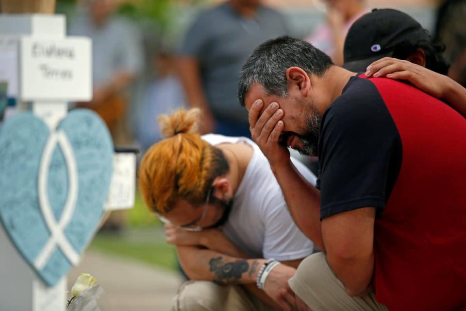 Vincent Salazar (der), padre de Layla Salazar, llora al arrodillarse frente a la cruz con el nombre de su hija en un monumento fúnebre por las víctimas  del tiroteo en la escuela primaria de Uvalde (AP)