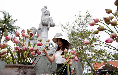 A woman arranges flower in front of a monument in a museum during the 50th anniversary of the My Lai massacre in My Lai village, Vietnam March 15, 2018. REUTERS/Kham