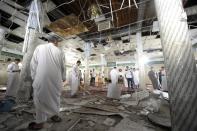Saudi men gather around debris following a blast inside a mosque, in the mainly Shiite coastal town of Qatif, 400 kms east of Riyadh, on May 22, 2015