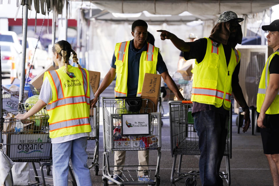 Volunteers position grocery carts to fill up vehicles with food boxes at the St. Mary's Food Bank Wednesday, June 29, 2022, in Phoenix. Long lines are back at outside food banks around the U.S. as working Americans overwhelmed by inflation increasingly seek handouts to feed their families. Many people are coming for the first time amid the skyrocketing grocery and gas prices. (AP Photo/Ross D. Franklin)