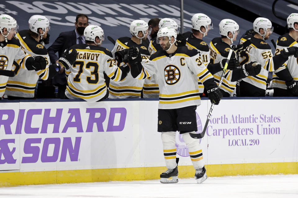 Boston Bruins center Patrice Bergeron is congratulated for his second-period goal against the New York Islanders in an NHL hockey game Saturday, Feb. 13, 2021, in Uniondale, N.Y. (AP Photo/Adam Hunger)