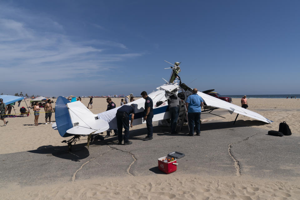 A small plane that was pulled from the water after it crashed into the ocean rests on the beach in Huntington Beach, Calif., Friday, July 22, 2022. The plane towing a banner crashed in the ocean Friday during a lifeguard competition that turned into a real-life rescue along the popular beach. (AP Photo/Jae C. Hong)