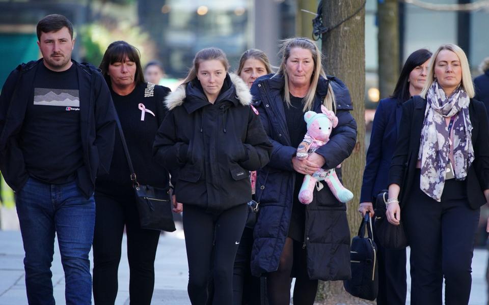 Olivia's mother clutches her teddy bear as she arrives at court, she described her daughter as a 'girly girl' who 'had her own style' - Peter Byrne