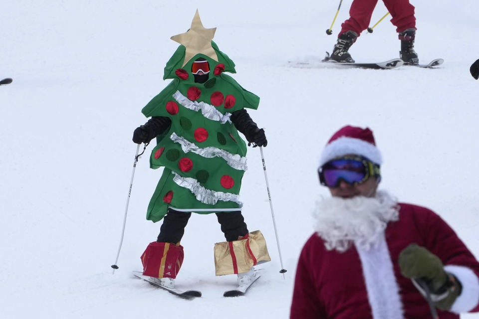 A skier dressed as a Christmas tree skis for charity at the Sunday River Ski Resort, Sunday, Dec. 11, 2022, in Newry, Maine. (AP Photo/Robert F. Bukaty)